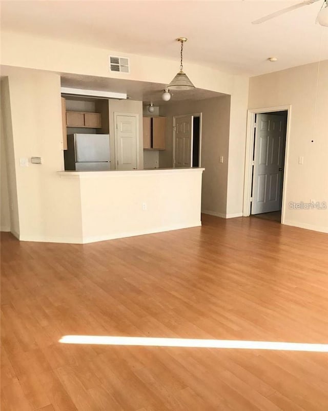 unfurnished living room with a ceiling fan, baseboards, visible vents, and wood finished floors