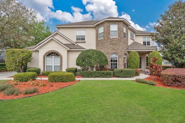 view of front of property with brick siding, stucco siding, a shingled roof, and a front lawn