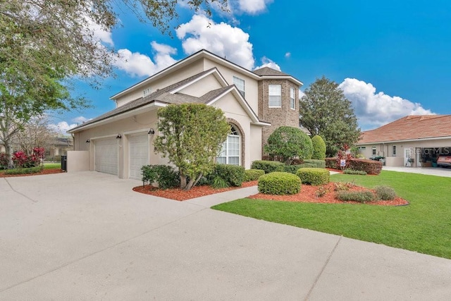 traditional home with a front yard, an attached garage, driveway, and stucco siding