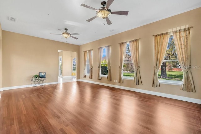 spare room featuring ceiling fan, visible vents, baseboards, and wood finished floors