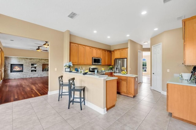 kitchen featuring light tile patterned floors, visible vents, a peninsula, stainless steel appliances, and light countertops