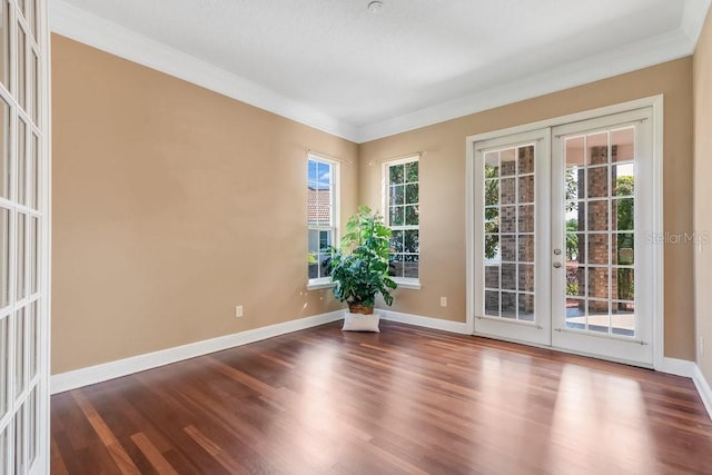 empty room featuring french doors, baseboards, wood finished floors, and ornamental molding