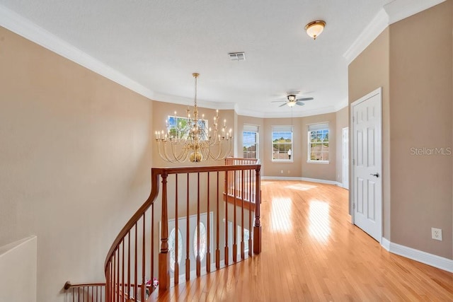 corridor with light wood-type flooring, baseboards, visible vents, and crown molding