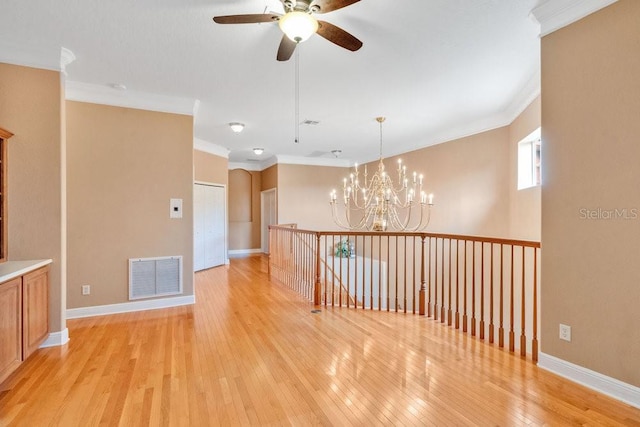 empty room with visible vents, light wood-style flooring, baseboards, and ornamental molding