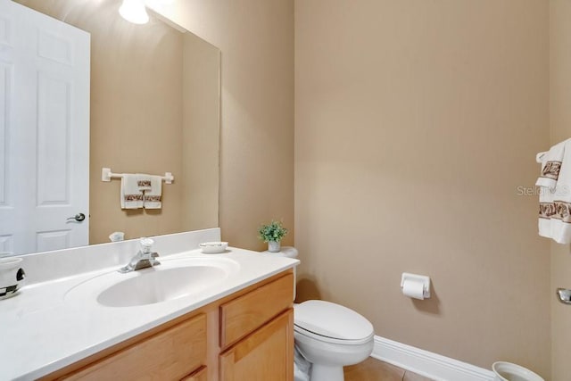 half bath with vanity, toilet, baseboards, and tile patterned flooring