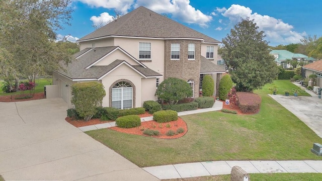 traditional-style home featuring stucco siding, driveway, roof with shingles, and a front yard