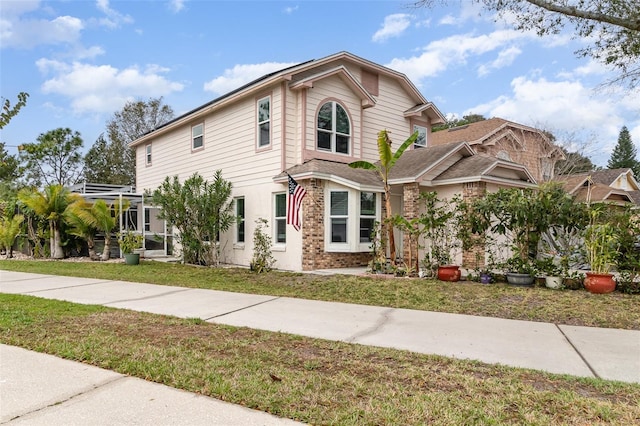 view of front of property with a lanai, a front lawn, and brick siding