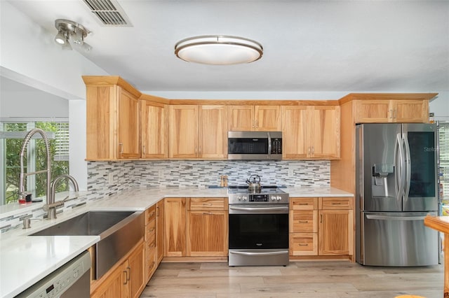 kitchen with appliances with stainless steel finishes, light countertops, visible vents, and tasteful backsplash