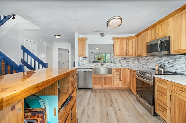 kitchen with visible vents, decorative backsplash, appliances with stainless steel finishes, light wood-style floors, and a sink