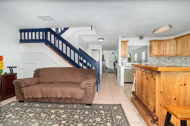 living area featuring light tile patterned floors, stairway, and visible vents