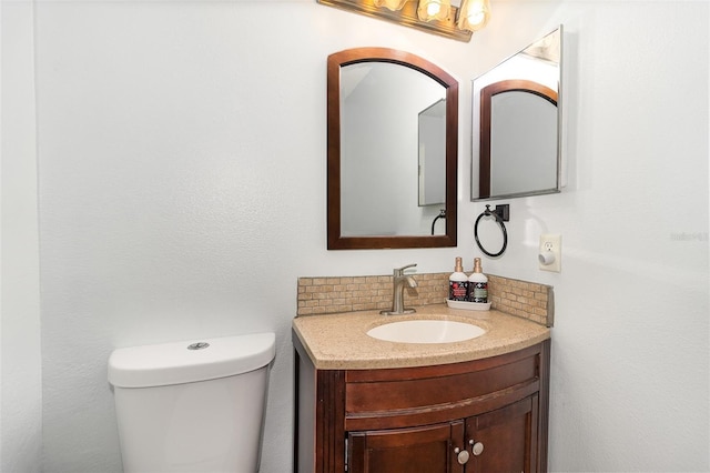 bathroom with toilet, vanity, and decorative backsplash