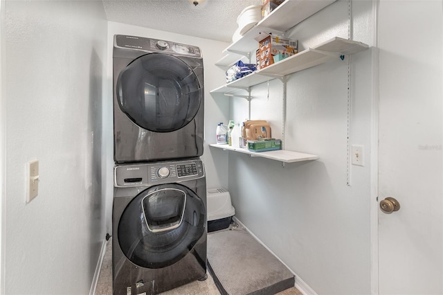 washroom featuring stacked washer / drying machine, laundry area, a textured ceiling, and baseboards