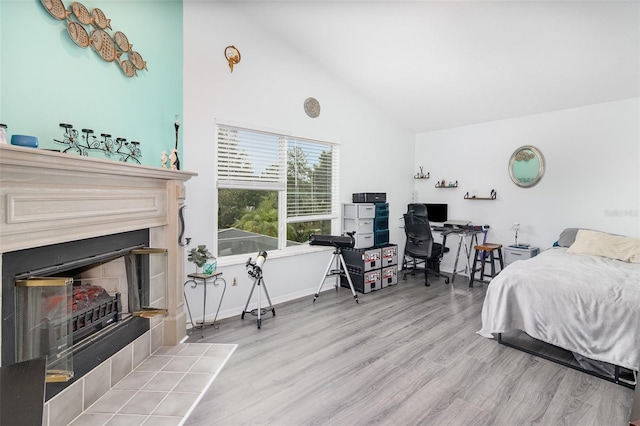 bedroom with high vaulted ceiling, baseboards, a fireplace, and light wood finished floors