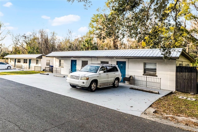 single story home featuring metal roof and fence