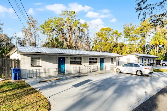 single story home with metal roof, brick siding, and fence