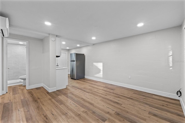 unfurnished room featuring baseboards, a wall mounted AC, light wood-style flooring, and recessed lighting