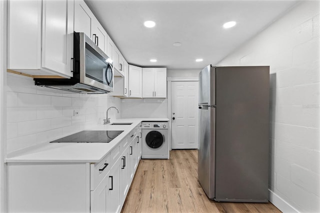 kitchen with light wood-style flooring, white cabinetry, light countertops, appliances with stainless steel finishes, and washer / dryer