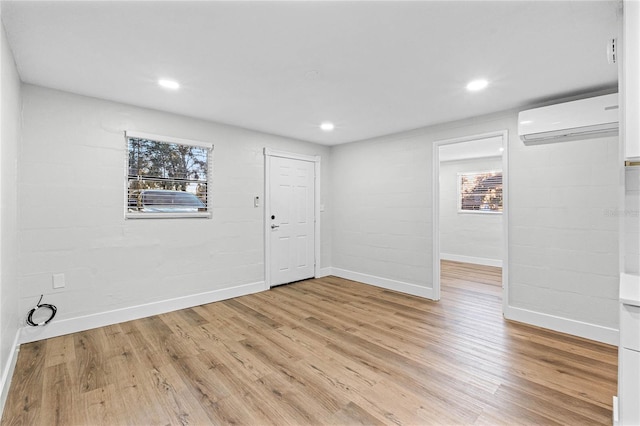 unfurnished room with recessed lighting, baseboards, light wood finished floors, and a wall mounted AC