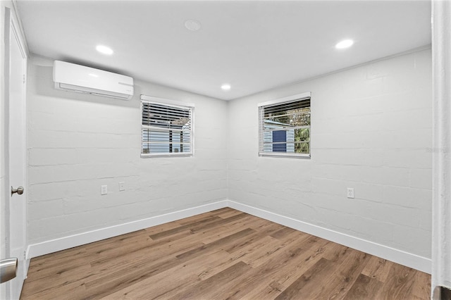 below grade area with wood finished floors, plenty of natural light, and a wall mounted AC