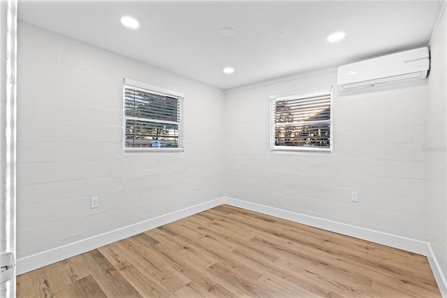 empty room with an AC wall unit, plenty of natural light, wood finished floors, and baseboards