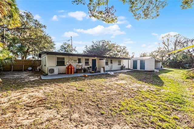 back of house featuring a storage shed, an outbuilding, fence, a yard, and a patio area