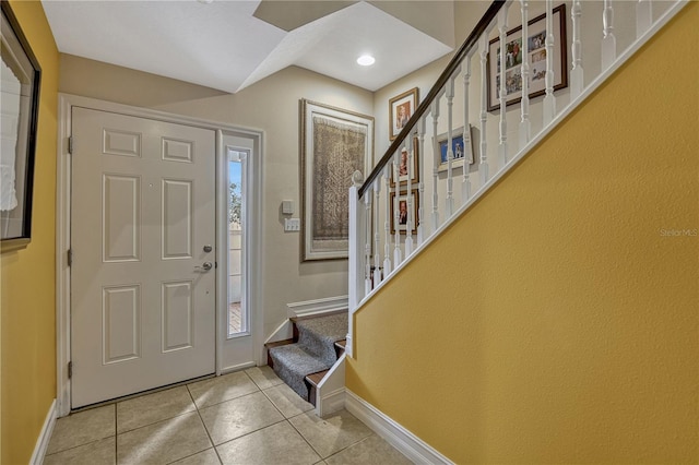 foyer entrance featuring a healthy amount of sunlight, light tile patterned floors, baseboards, and stairway