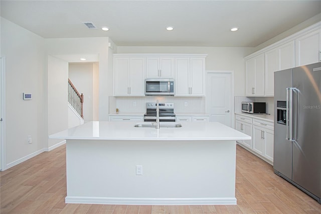 kitchen with tasteful backsplash, visible vents, stainless steel appliances, light wood-type flooring, and a sink