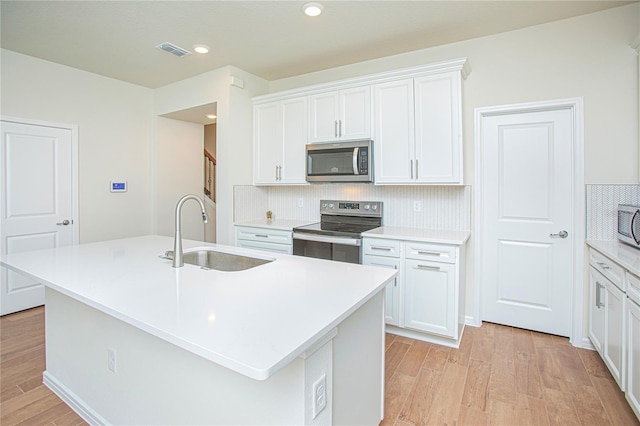 kitchen with tasteful backsplash, visible vents, appliances with stainless steel finishes, light wood-style floors, and a sink