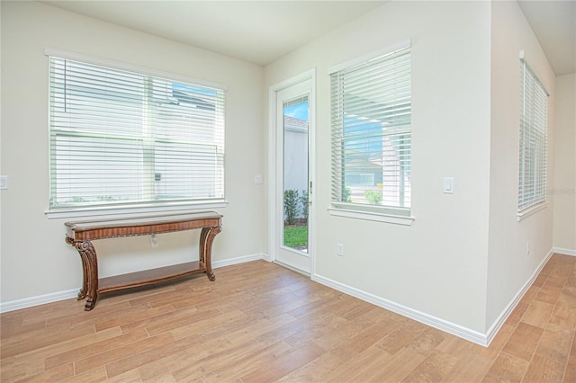 doorway to outside with light wood-style flooring and baseboards