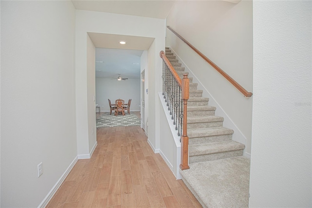 staircase featuring ceiling fan, wood finished floors, and baseboards