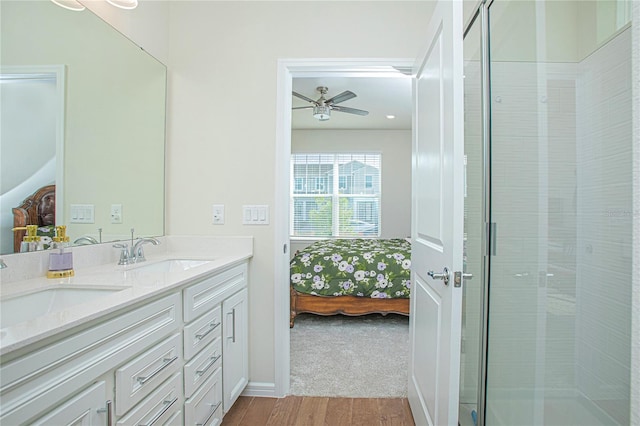 ensuite bathroom featuring double vanity, ensuite bath, wood finished floors, a shower stall, and a sink