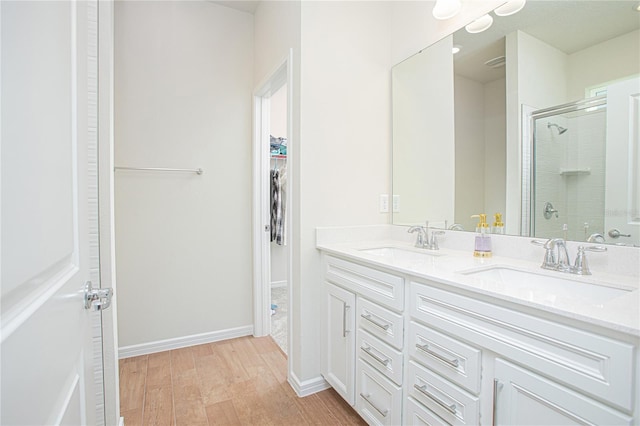 bathroom with a shower stall, baseboards, a sink, and wood finished floors