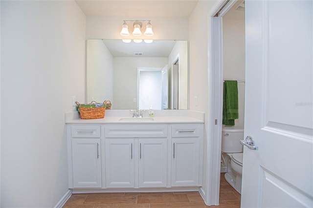 bathroom featuring toilet, baseboards, vanity, and wood tiled floor