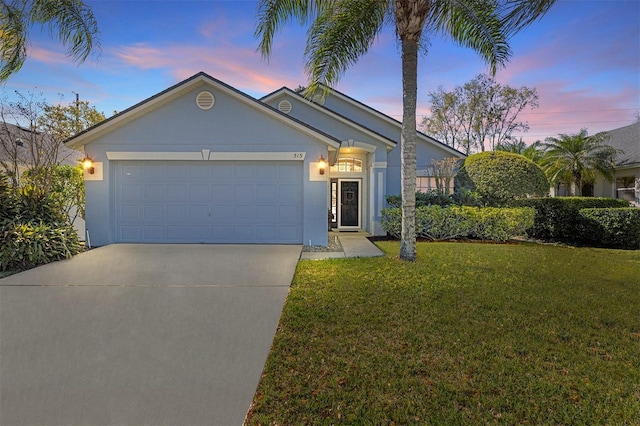 view of front of house with an attached garage, a yard, concrete driveway, and stucco siding