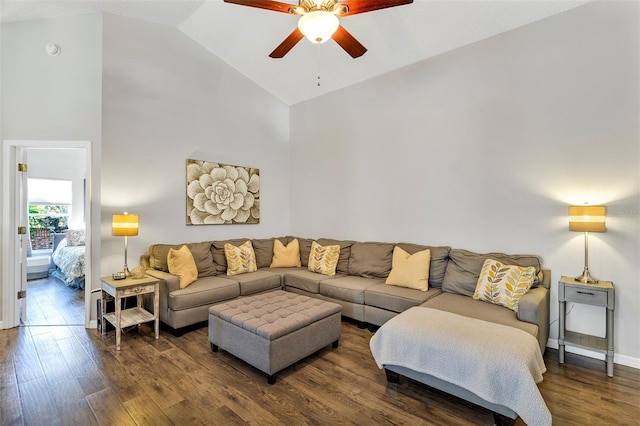 living area with high vaulted ceiling, dark wood finished floors, a ceiling fan, and baseboards