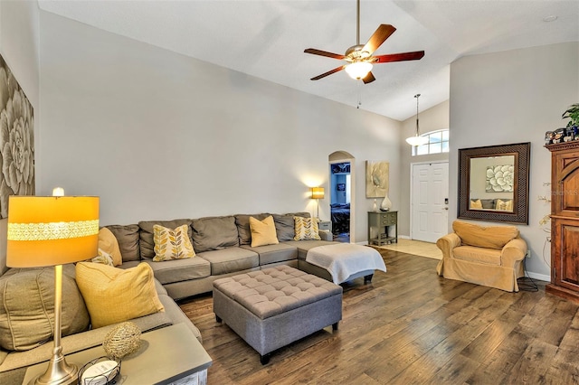 living room featuring arched walkways, baseboards, ceiling fan, wood finished floors, and high vaulted ceiling