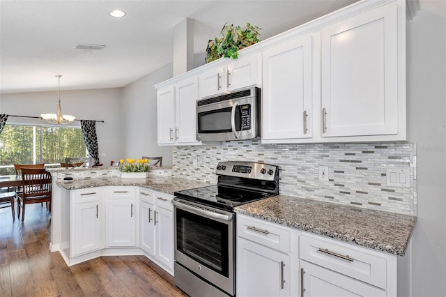 kitchen with appliances with stainless steel finishes, dark wood-style flooring, a peninsula, vaulted ceiling, and white cabinetry