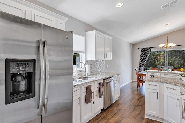 kitchen with tasteful backsplash, visible vents, lofted ceiling, stainless steel appliances, and a sink