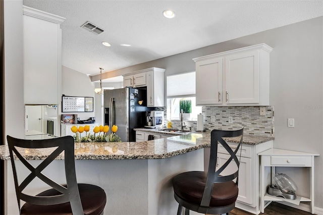 kitchen featuring decorative backsplash, a breakfast bar area, a sink, and stainless steel fridge with ice dispenser