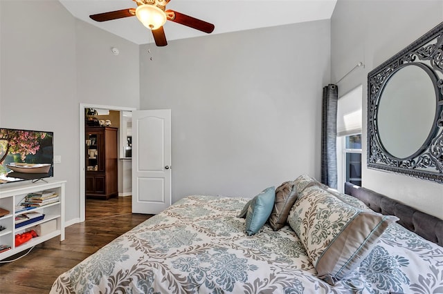 bedroom with ceiling fan, dark wood finished floors, a towering ceiling, and baseboards