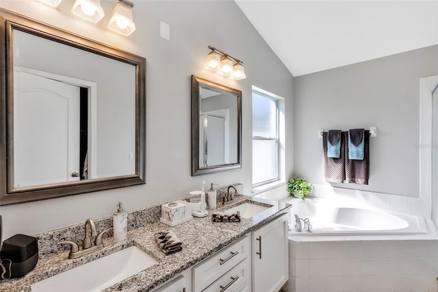 full bathroom with tiled tub, vaulted ceiling, a sink, and double vanity