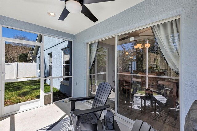 sunroom featuring ceiling fan with notable chandelier