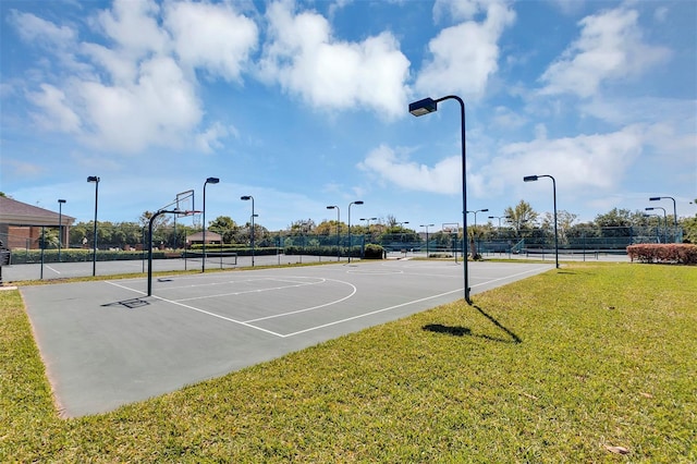 view of sport court with community basketball court, fence, and a yard