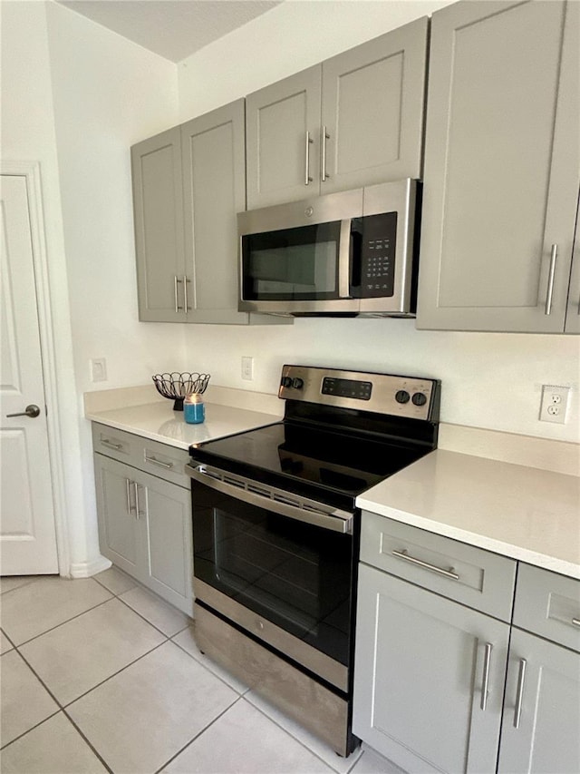 kitchen featuring light countertops, appliances with stainless steel finishes, light tile patterned flooring, and gray cabinets