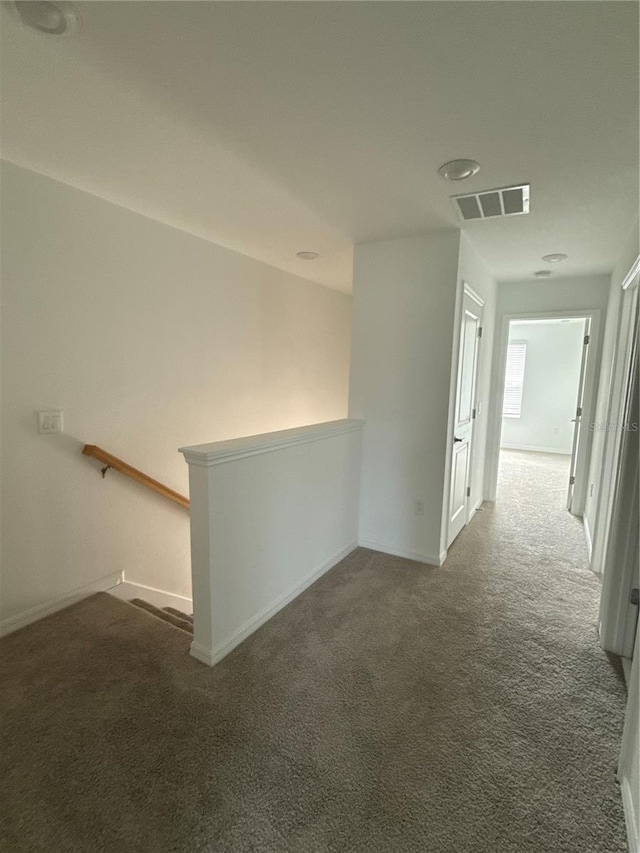 hallway featuring visible vents, carpet flooring, and an upstairs landing