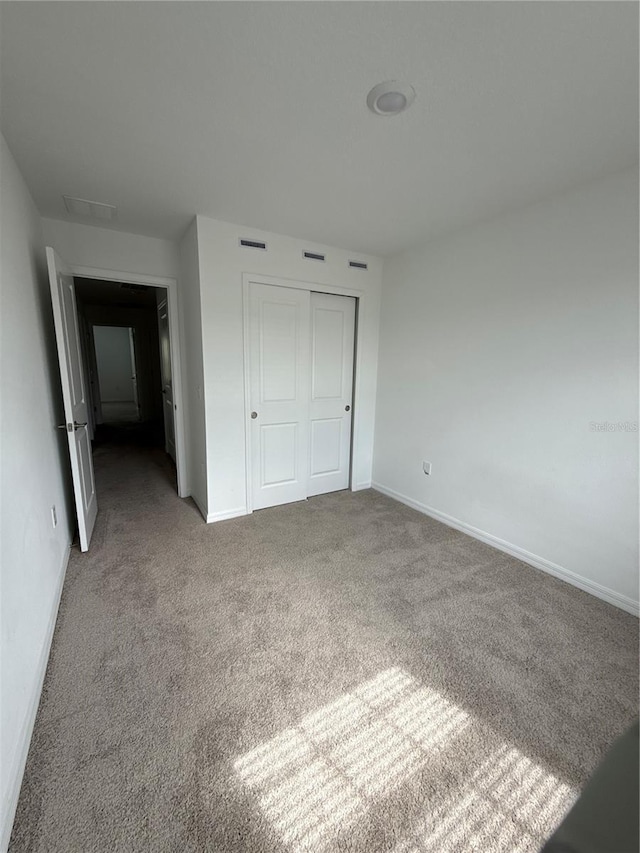 unfurnished bedroom featuring visible vents, a closet, baseboards, and carpet flooring