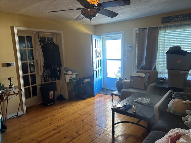 living room featuring ceiling fan, light hardwood / wood-style flooring, and a textured ceiling