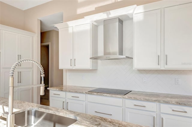 kitchen featuring tasteful backsplash, white cabinetry, sink, wall chimney range hood, and black electric cooktop