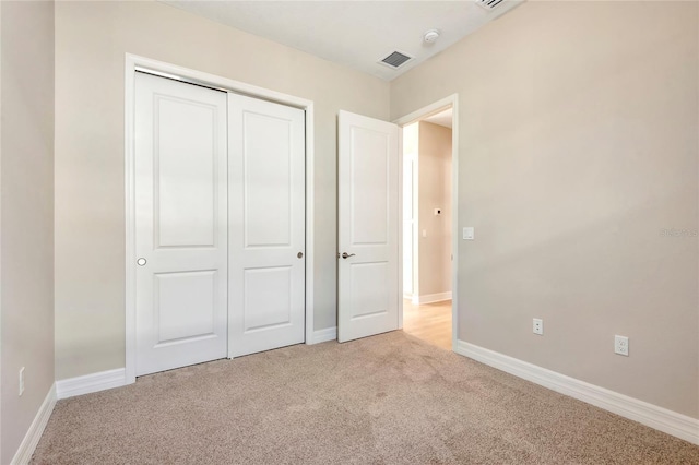 unfurnished bedroom featuring light colored carpet and a closet