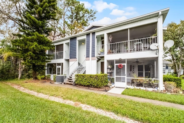 multi unit property with central air condition unit, a sunroom, and a front yard